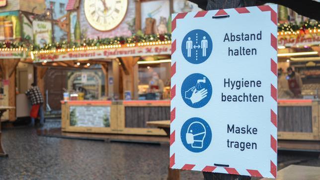 Hinweisschilder weisen auf dem Weihnachtsmarkt in Frankfurt auf die dort herrschende Maskenpflicht hin.