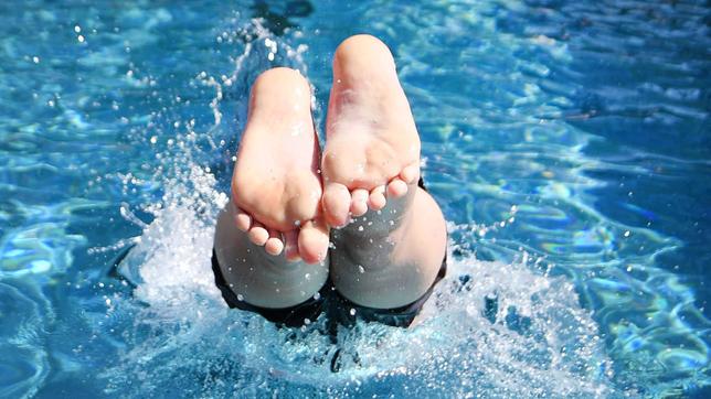 Bild: dpa/Bernd Thissen Ein Junge springt mit einem Kopfsprung in das Wasser eines Freibads