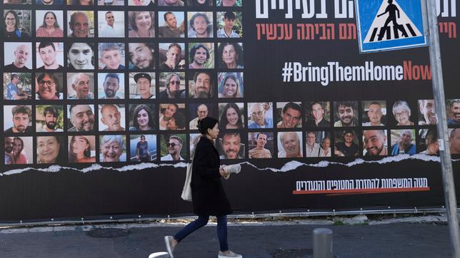 Eine Frau geht in Jerusalem an einem Plakat vorbei, das die Rückkehr von etwa 240 Geiseln fordert, die während des Hamas-Angriffs entführt worden waren. 
