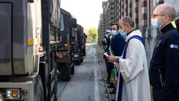 Militärtransporter fahren an einem Priester vorbei
