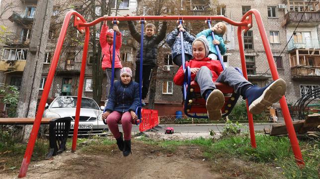 Ukrainische Kinder sitzen auf einem Spielgerüst