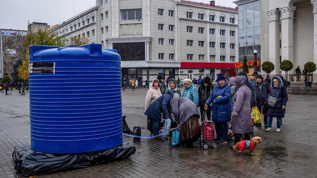 Menschen stehen in Cherson an einem öffentlichen Brunnen an.