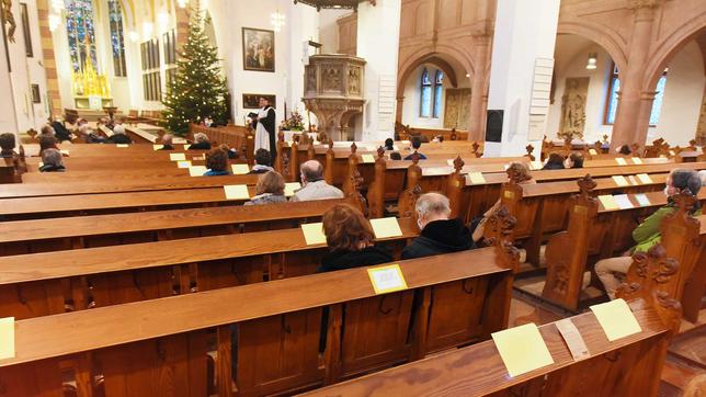 Gläubige sitzen mit Abstand in einer Kirche