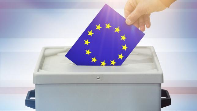 Hand steckt eine Europaflagge in eine Wahlurne