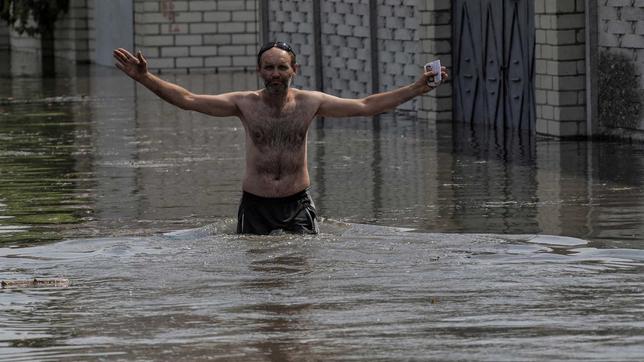 Ein halbnackter Mann steht in den Fluten des zerstörten Kachowka-Staudamms