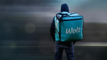Eine Person mit dem Rücken zur Kamera und einem Rucksack mit der Aufschrift "Wolt Partner".