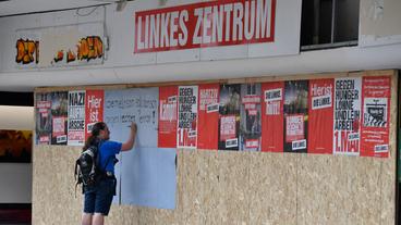 Ein Mann trägt sich am Oberhausener Friedensplatz auf ein Plakat gegen rechte Gewalt am provisorischen Fensterersatz des Büros der Partei "Die Linke" in eine Unterschriftenliste ein.