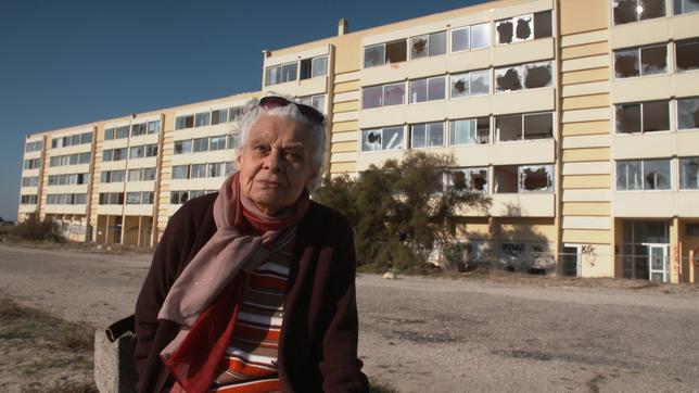 Eine ältere Frau vor der Ruine eines Appartementhauses