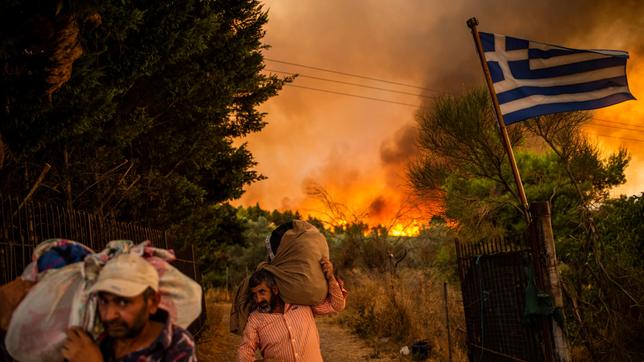 Bild: picture alliance/dpa/Angelos Tzortzinis Menschen fliehen vor einem Feuer in Griechenland.
