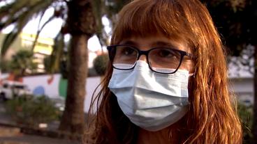 Eine Frau mit Mund-Nasen-Schutz schaut in die Kamera.