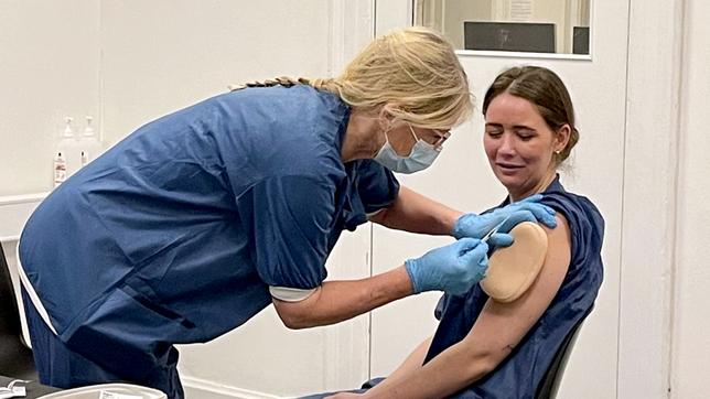 Ein Frau gibt einer anderen Frau eine Impfung in den Oberarm