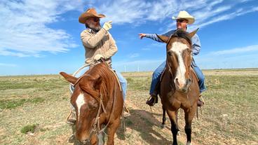 Zwei Männern mit Cowboyhüten auf ihren Pferden.