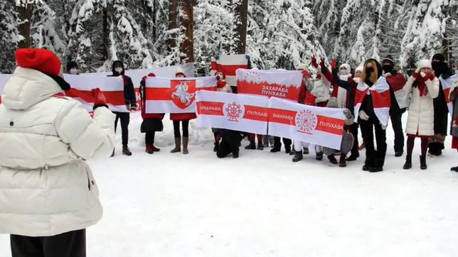 Menschen halten in einem Wald Flaggen der Opposition in Belarus hoch.