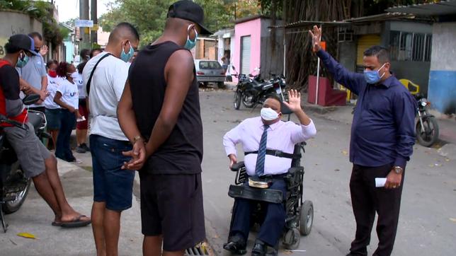 Ein Mann im Rollstuhl umringt von jungen Männern.