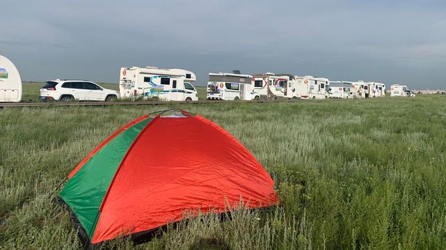 Campingmobile an einer Straße, im Vordergrund ein Zelt.
