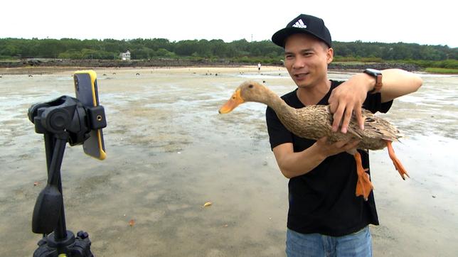 Ein Mann hält eine Ente in eine Handykamera