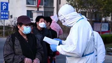 Chinesen stehen mit Maske in einer Reihe zum einem Coronatest.