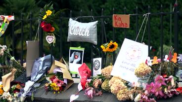 Blumen und Trauerbekundungen an einem Zaun