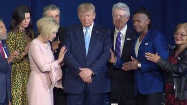 Donald Trump in der Mitte mehrere Menschen, die für ihn beten.