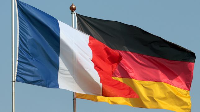 Die Flaggen Deutschlands und Frankreichs wehen vor blauem Himmel im Wind.
