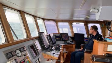 Ein Mann auf der Kommandobrücke eines Schiffes.