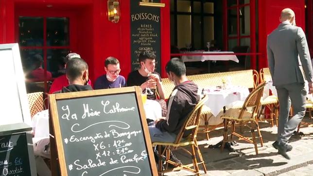 Menschen sitzen vor einem Restaurant in Paris.
