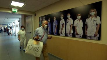 In einem Krankehausflur hängt ein Bild mit Krankenhauspersonal.