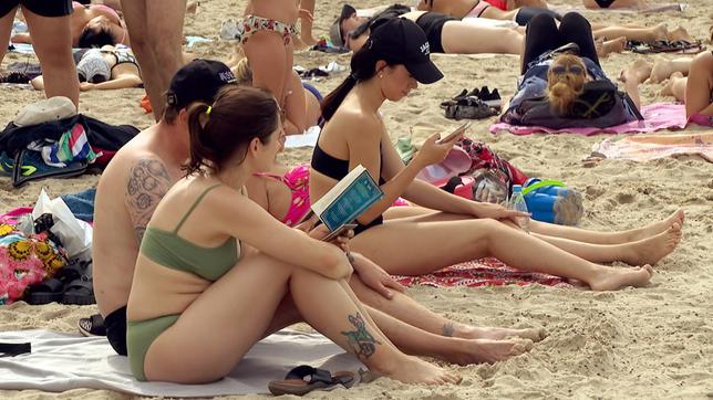 Menschen sitzen im Sand am Strand.