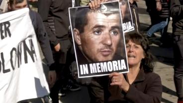Eine Frau hält ein Foto des Separatist Yvan Colonna hoch.