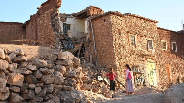 Kinder vor einem vom Erdbeben zerstörten Haus