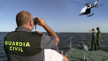 Polizisten auf einem Boot und im Hubschrauber suchen nach Flüchtlingen
