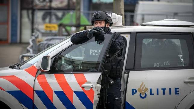 Ein Polizist steht an der Tür seines Dienstwagens.