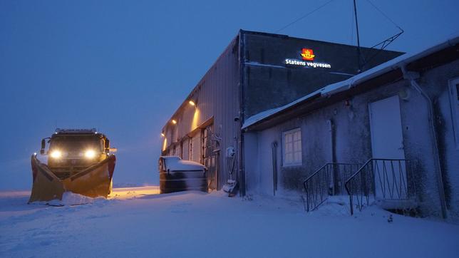 Schneepflug in Norwegen neben einem großen Gebäude