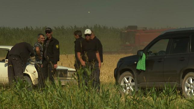 Bauern und Polizisten vor einem Kornfeld