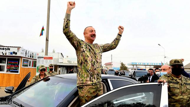 Ein Mann in Tarnkleidung triumphiert in der Tür einer Limousine.