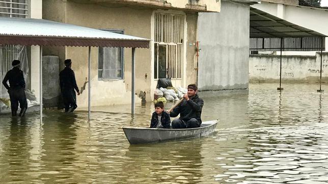 Ein Mann mit einem Kind in einem Boot auf einer überschwemmten Straße