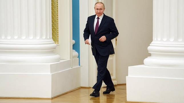 Wladimir Putin läuft zwischen zwei Säulen.