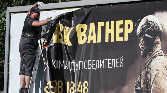 Ein Mann entfernt ein großes Werbeplakat der "Wagner-Gruppe" in St. Petersburg