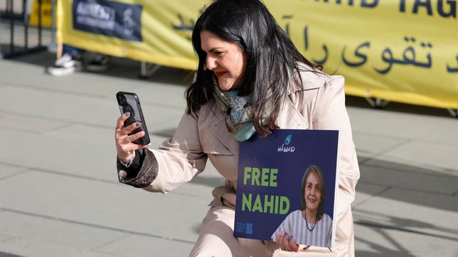 Eine Frau mit einem Plakat in der Hand macht ein Foto von sich.