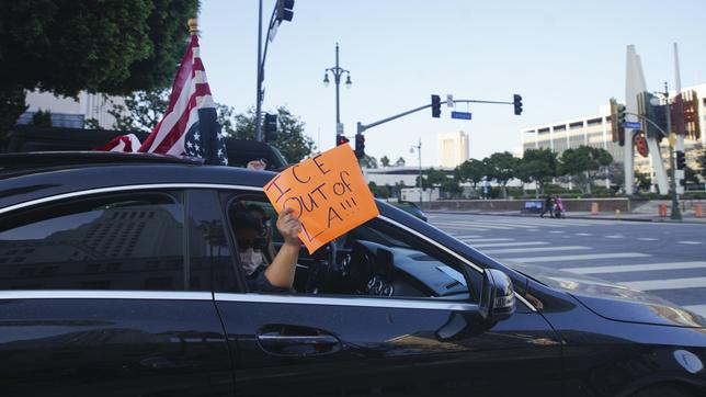 Bild: picture alliance / Anadolu | Katie McTiernan Protest aus dem Auto mit dem Schild "ICE raus aus LA!"