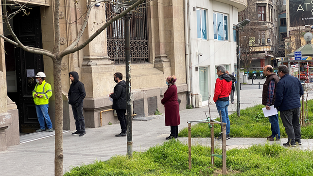 Menschen stehen mit Abstand in einer Schlange vor dem Eingang eines Gebäudes.