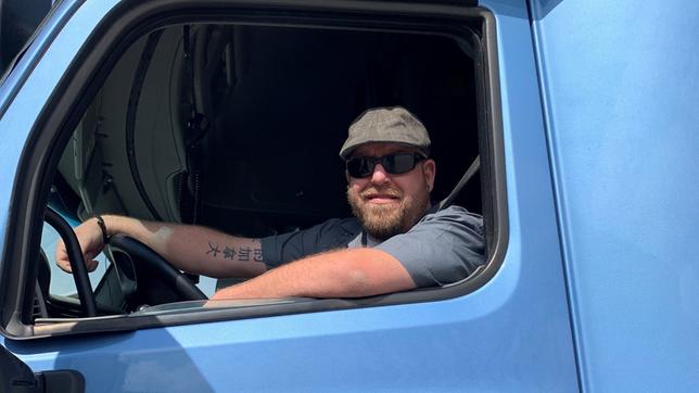 Ein Mann schaut aus dem Seitenfenster eines Lastwagens.