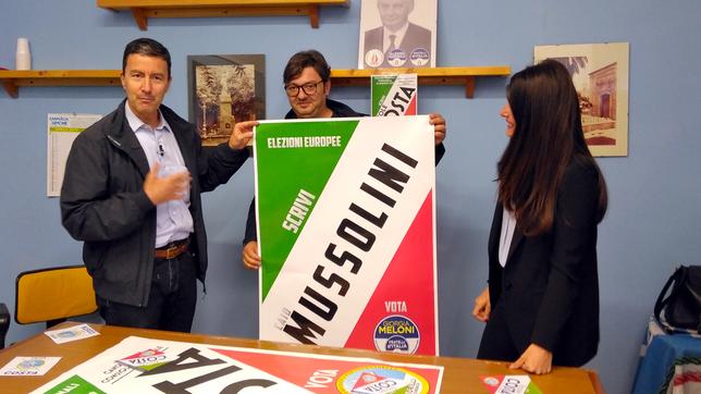 Ein Mann hält ein Wahlkampfplakat mit der Aufschrift "Mussolini".