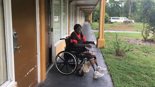 Eine Frau in einem Rollstuhl auf der Veranda eines Motels
