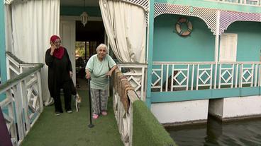 Ältere Frau mit Gehstock auf Steg am Hausboot