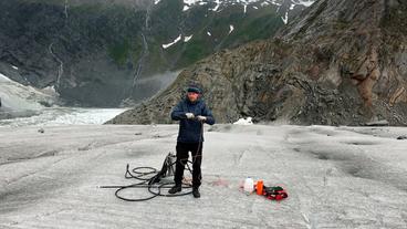 Der Forscher Eran Hood mit Instrumenten, im Hinterghrund Gebirgslandschaft