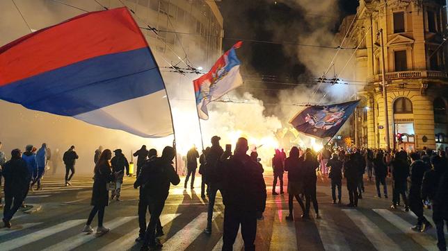 Menschen auf einer nächtlichen Straße mit russischen Flaggen und bengalischen Feuern