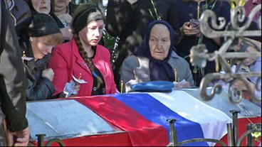 Frauen an einem mit der russischen Fahne geschmückten Sarg