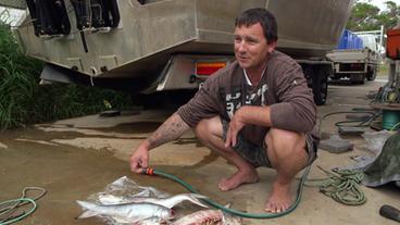 Mark McMillan mit toten Fischen