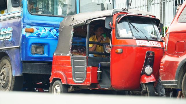 Ein TukTuk mit Fahrer in einer Reihe von Fahrzeugen